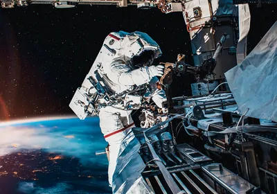 Astronaut working on the space station in outer space, with the Earth and sun in the background.